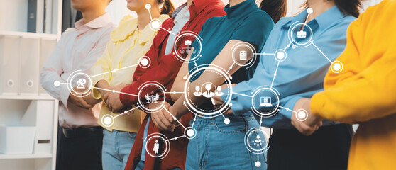 Diverse group of young professionals standing together with digital graphic icons symbolizing teamwork and collaboration in modern workspace environment. Amity