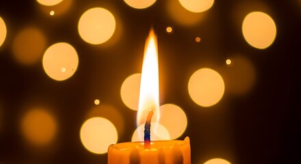 A single brightly burning candle flame illuminates the darkness against a backdrop of warm glowing bokeh lights