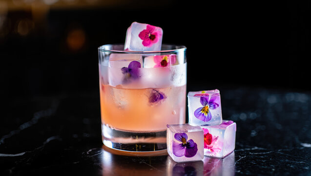 Cocktail with floral ice cubes on black marble table, culinary art, mixology inspiration, beverage presentation, bar menu design, event promotion, creative food styling
