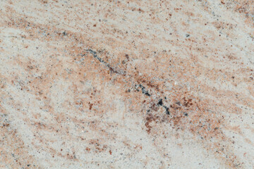 Jasna granitowa powierzchnia z beżowymi żyłkami, naturalna kamienna tekstura.