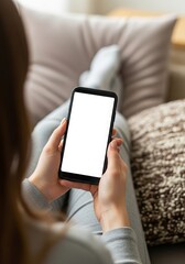Woman relaxing at home using a smartphone with a blank white screen for app promotion or mobile advertising in a cozy and comfortable setting