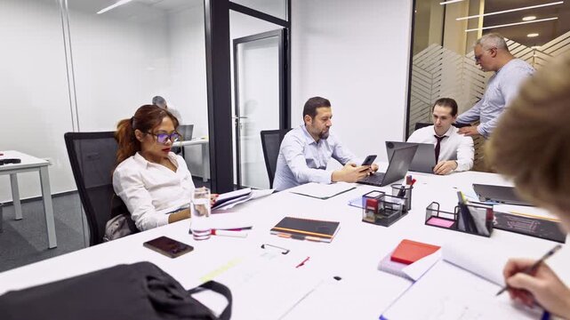 Professional business coworkers actively engage in collaborative work, utilizing laptops and phones during a productive office meeting. - Powered by Adobe