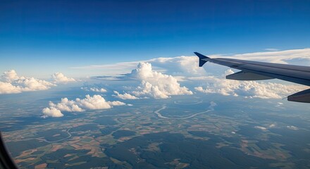 Fototapeta premium A view from an airplane window, showcasing a vast expanse of clouds and a glimpse of the earth below.