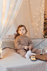 Little boy playing with a toy. Child is sad sitting on the bed. Brown colors.