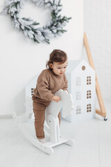 Little boy playing with toy horse. Child swinging on a rocking horse on a white background