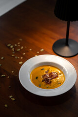 Creamy pumpkin soup served in bowl with garnish