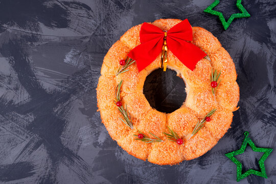 Bread Christmas wreath with cheese topped with rosemary and red berries on the gray table. Festive monkey bread. Top view, copy space