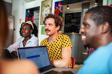 Young adults collaborating with laptops in a cafe, focused and engaged