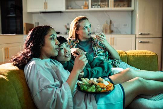 Adult friends watching movie at home, surprised and focused