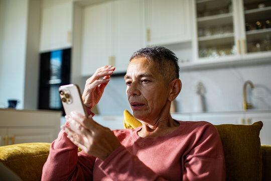 Senior woman concerned while using smartphone at home kitchen