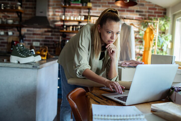 Young woman focused on laptop running small business at home