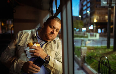 Tired mature man dozing with coffee on city bus at night