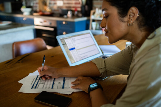 Young adult woman focused on bills at home kitchen table