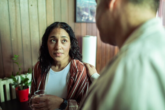 Adult woman looking worried as adult man offers comfort at home