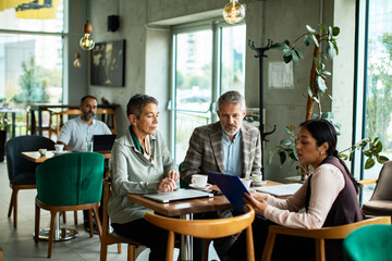 Senior couple meeting adult financial advisor in cafe, looking serious