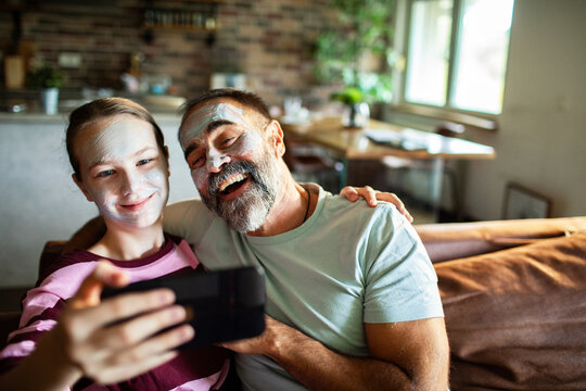 Mature father and teen daughter laughing during spa selfie at home