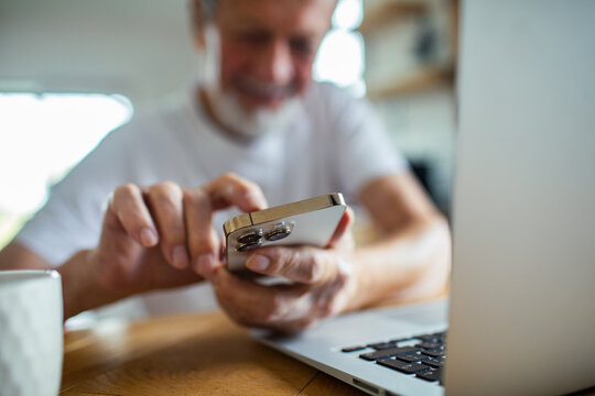 Senior man paying bills on smartphone at home, focused - Powered by Adobe