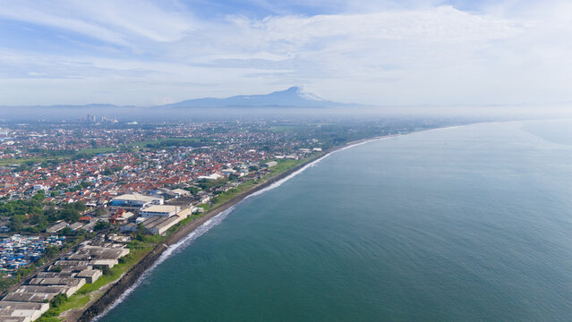Aerial view of Mount Slamet from Cilacap shows the hazy houses on the Indonesian coast, suitable for travel brochures, websites, and environmental articles.