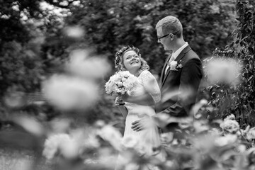 Bride and groom in a romantic outdoor setting, surrounded by blooming flowers, sharing a joyful moment, capturing the essence of love and celebration in a beautiful garden
