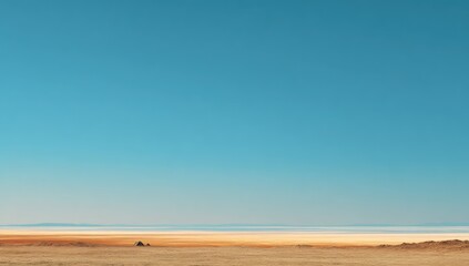 Vast, hazy desert landscape stretches to a pale horizon beneath a vibrant blue sky