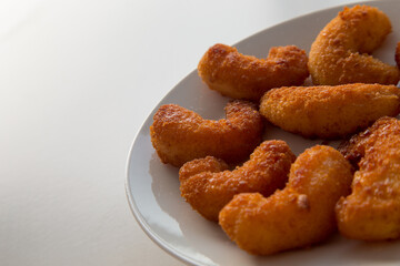 Gamberi impanati fritti su piatto bianco
