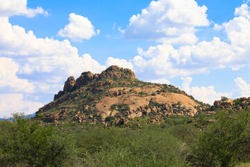 Scattered brown sandstone and rugged rock formations against a blue sky. Photographed in the Waterberg region. Panoramic view of the sandstone cliffs of the Waterberg. Namibia, Africa.