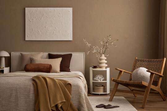 Neutral bedroom interior with rattan armchair,  mix of decorative pillows, layered blankets and soft lighting.