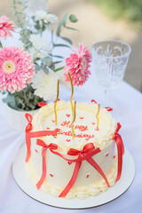 happy birthday cake with red bows on white background with pink flowers, celebration party, vertical photo 