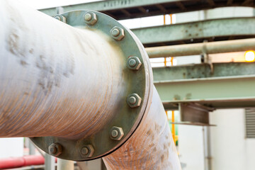 Close-up view of a large industrial pipe with bolted flange and supporting structure, highlighting engineering and infrastructure