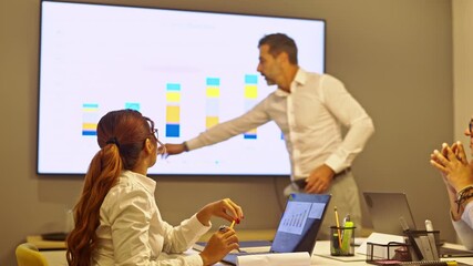 Business colleagues collaborate in a modern office meeting, attentively reviewing a data presentation on a large screen. They discuss financial performance, market trends, and strategic planning. - Powered by Adobe