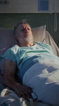 Shocked old man with pulsimeter and dripper wakes up in ward