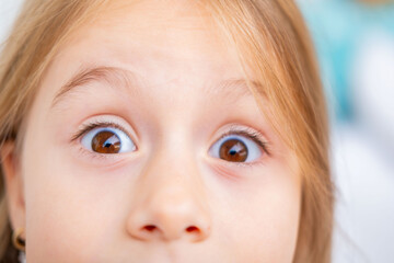 child's wide-open eyes and surprised expression, conveying shock, curiosity, astonishment, or fear in candid and emotional moment, bulging goggle eyes, upper face close-up, staring camera,