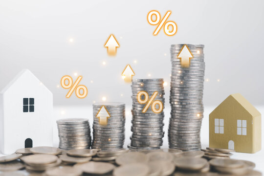 Rising stacks of coins with house models and glowing percentage symbols represent real estate investment growth, mortgage interest rates, and property finance concepts, ideal for market analysis.
