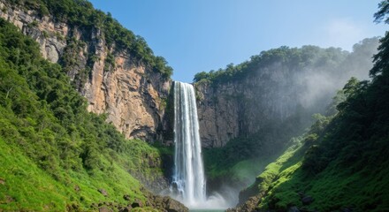 Majestic waterfall cascading down steep cliffs. Lush green forest surrounds the falls