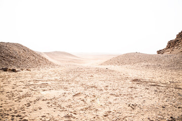 Vast desert landscape with gentle hills and clear sky during midday sun in an arid region