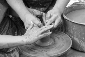 Retro style black and white photo depicting process of learning to make pottery with close-up of person's hands holding soft clay