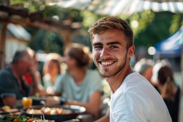 Young man smiling at outdoor gathering with friends