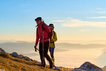 Fototapete Rund Extremsportarten Couple exploring stunning mountain landscape during early morning sunrise with clouds below  © Minet
