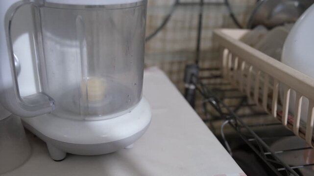 Close up shot of hands of unrecognizable woman adding fresh blueberries to blender while making fruit smoothie, 