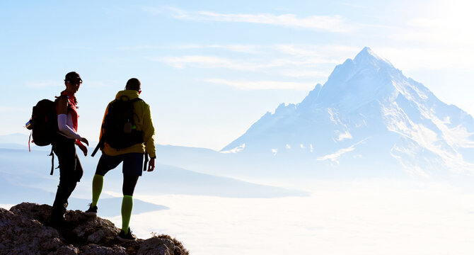Couple enjoying breathtaking view from mountain peak during sunset on a clear day - Powered by Adobe