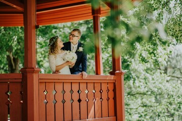 Joyful couple, an african american woman and a caucasian man, embrace on a gazebo balcony, surrounded by lush greenery, celebrating love and commitment in a romantic setting