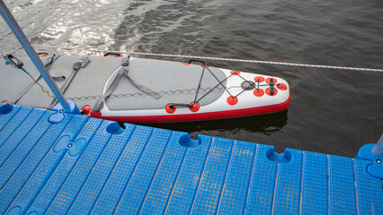 Inflatable SUP board by blue pontoon on water horizontal