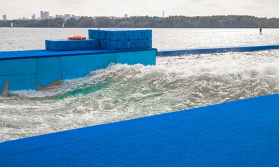 Artificial training wave for surfers on lake with blue platform