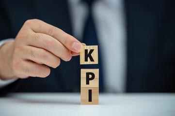 Naklejka premium Banner KPI concept with wooden block on blue background. Key Performance Indicator using Business Intelligence metrics to measure achievement versus planned target