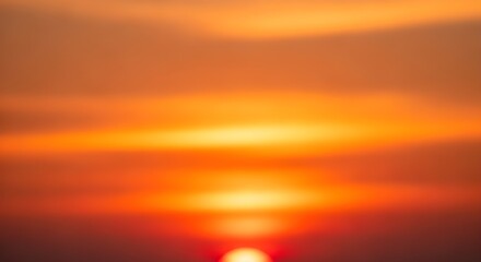 Vibrant orange sunset sky with soft clouds and reflection