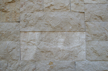 High-resolution beige stone wall texture featuring rough, natural rock surfaces and irregular block patterns. Ideal for backgrounds, architecture themes, construction materials, and design mockups.