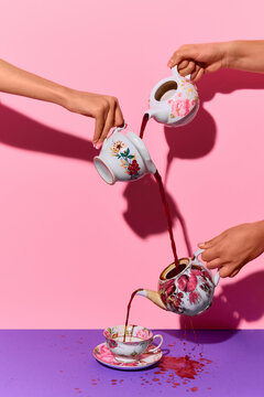 Multiple vintage teapots pouring tea into floral cup on pink and purple background. Concept of cozy cafe promos, menu artwork, tea service branding, drink culture stories, and editorial drink pieces.