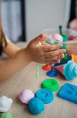 A little girl makes figurines out of colored airy plasticine, modeling dough. Hobbies for children's creativity, educational activities, development of fine motor skills of hands.