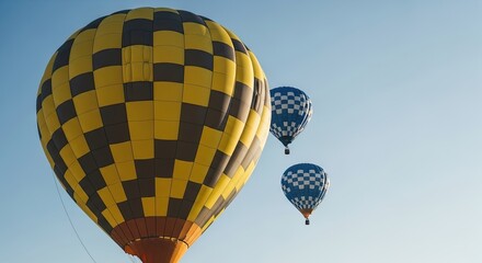 Three colorful hot air balloons with checkered patterns float peacefully through a clear blue sky during a beautiful sunny day, evoking a sense of adventure and freedom