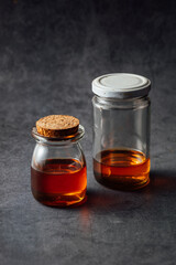 Glass jars with liquid contents on textured dark background